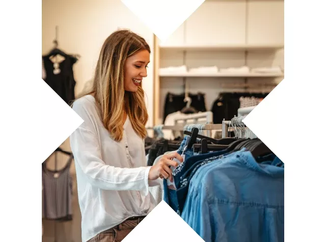 Mujer eligiendo ropa en una tienda, mostrando la facilidad de Pluxee Dotación para compras eficientes.