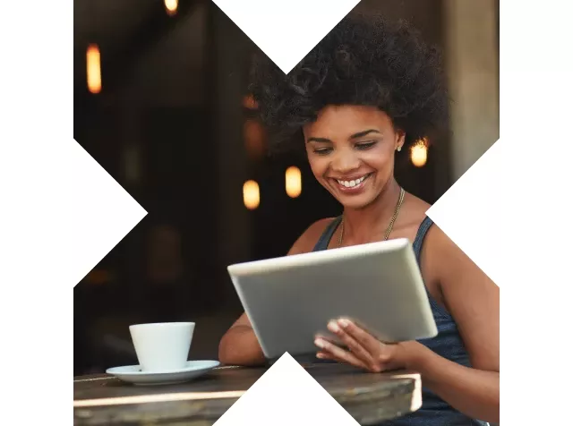 Mujer sonriente usando una tablet en un café, representando la conveniencia y flexibilidad que ofrece Pluxee Gastos para gestionar gastos de manera digital.