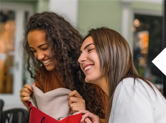 Dos mujeres están sonriendo al destapar un regalo
